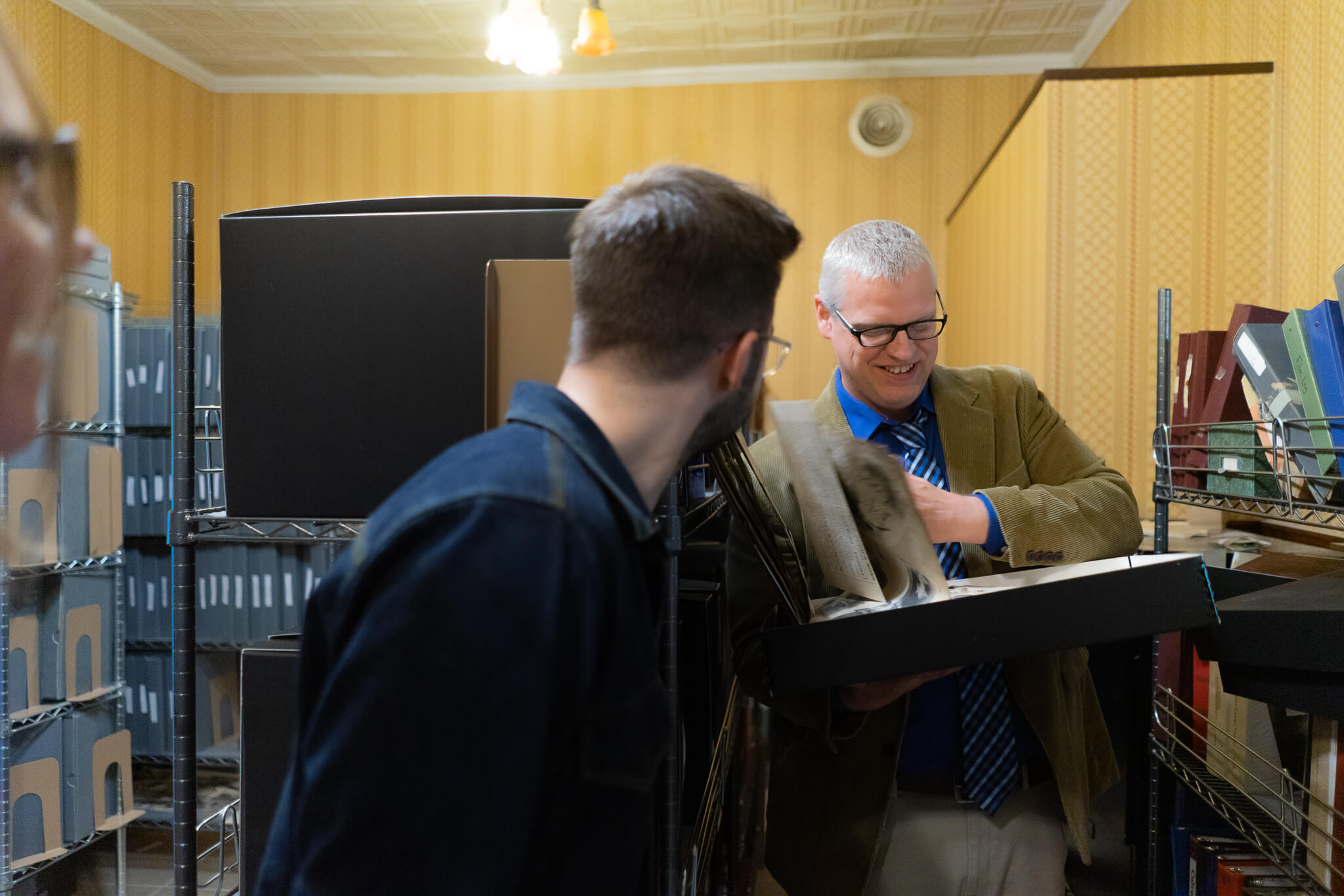 Culver Academies historian Jeff Kenney photographed in their archives flipping through old student scrapbooks.